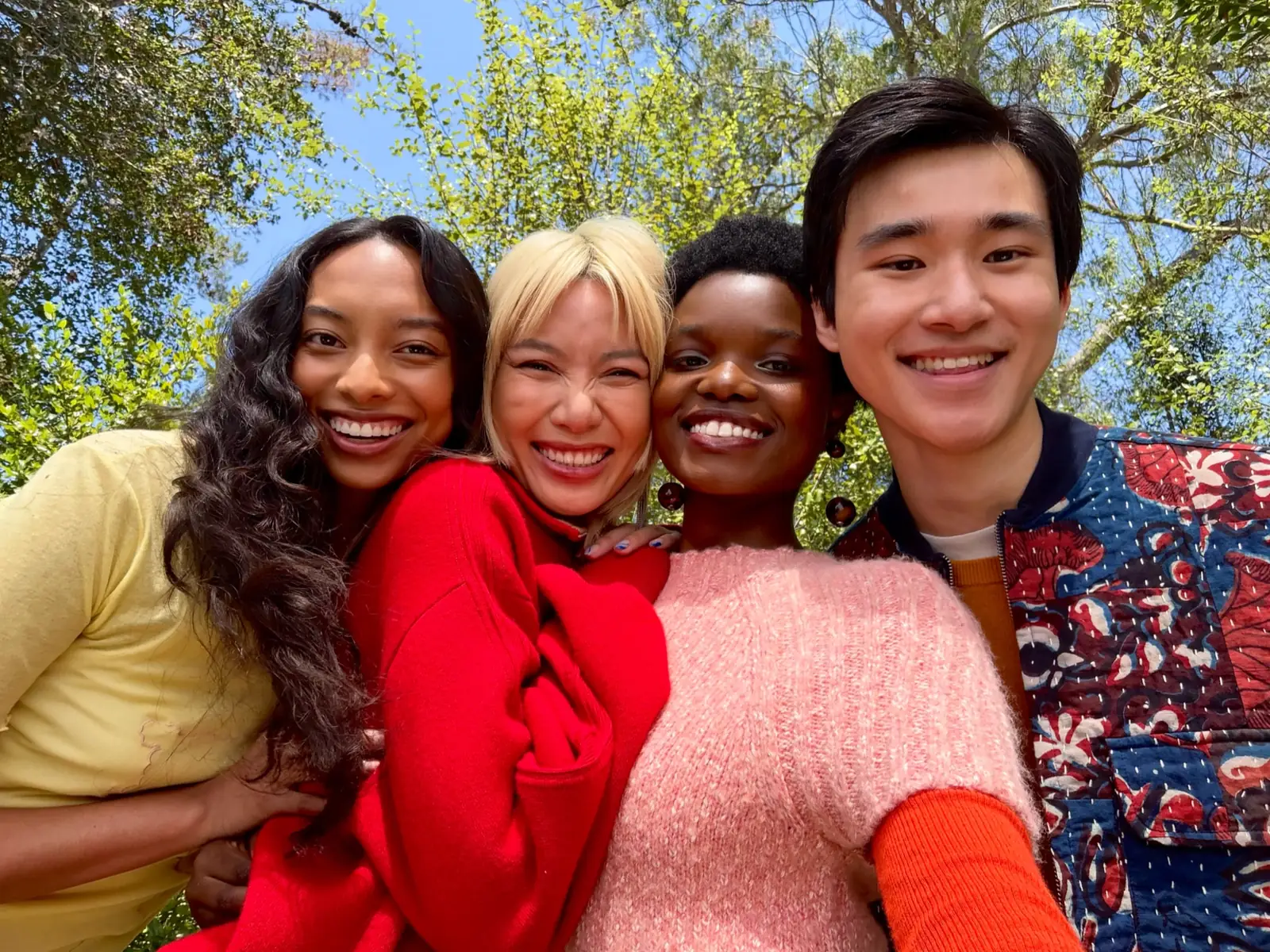 Four friends smile for a selfie outdoors